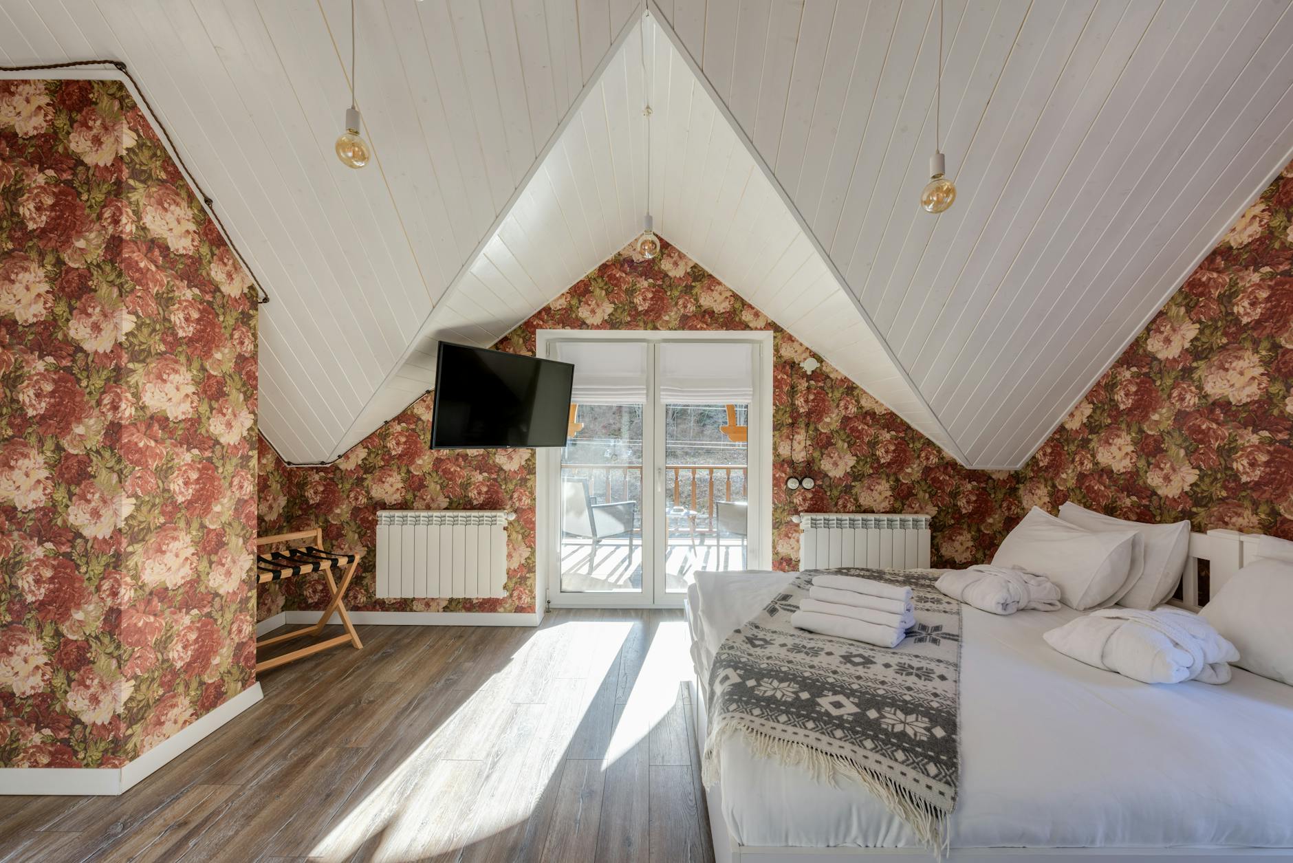Przytulna sypialnia na poddaszu z balkonem i kwiecistą tapetą