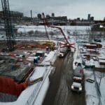 Zimowy plac budowy z dźwigiem i ciężarówkami na zaśnieżonym terenie