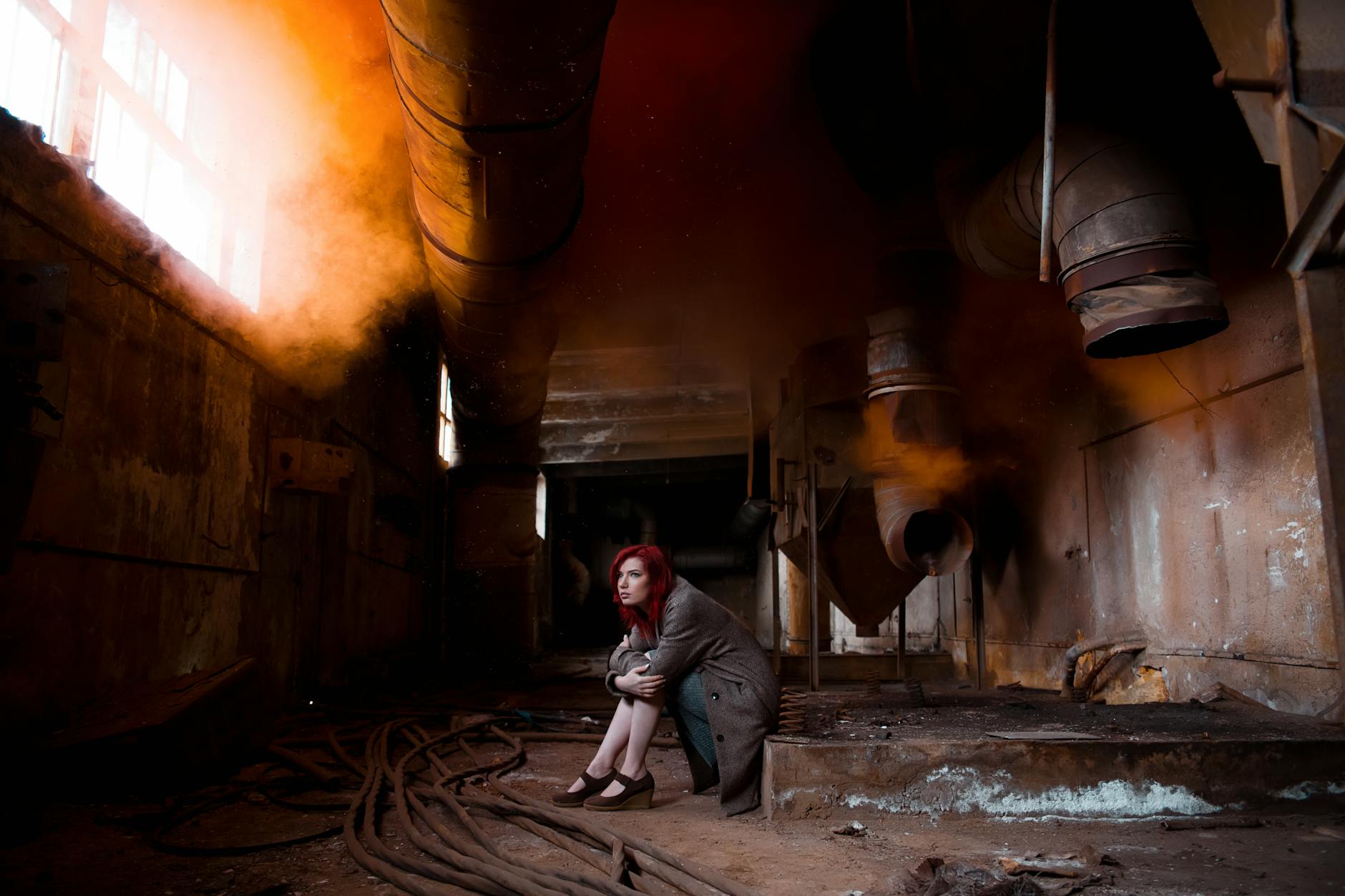 Kobieta wśród przemysłowych rur w pomarańczowej mgle