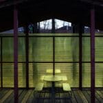 Zadaszona strefa wypoczynku z ławkami i żółtymi, półprzezroczystymi ścianami