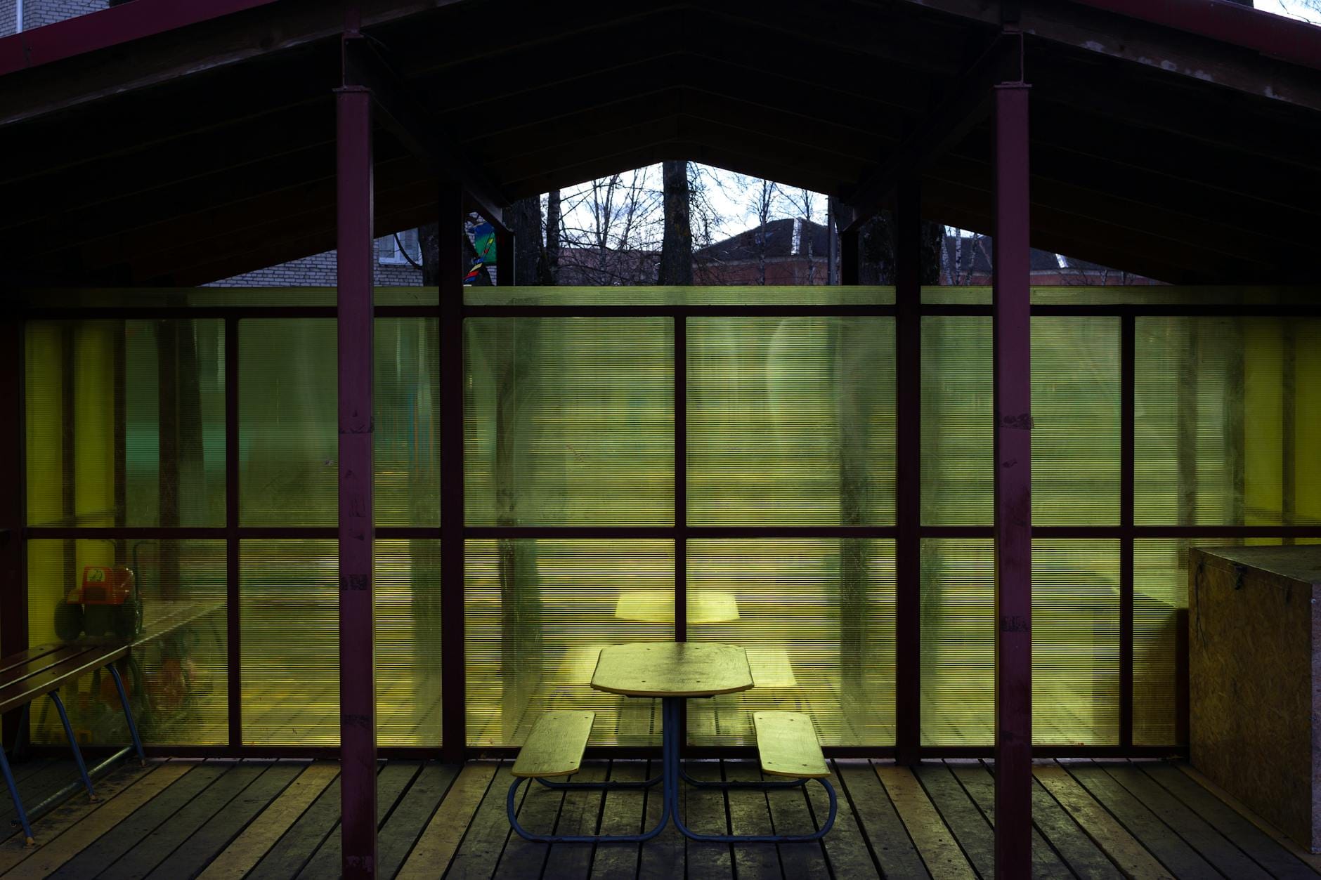 Zadaszona strefa wypoczynku z ławkami i żółtymi, półprzezroczystymi ścianami