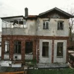 Zaniedbana kamienica z odsłoniętą ceglaną elewacją i wybitymi oknami