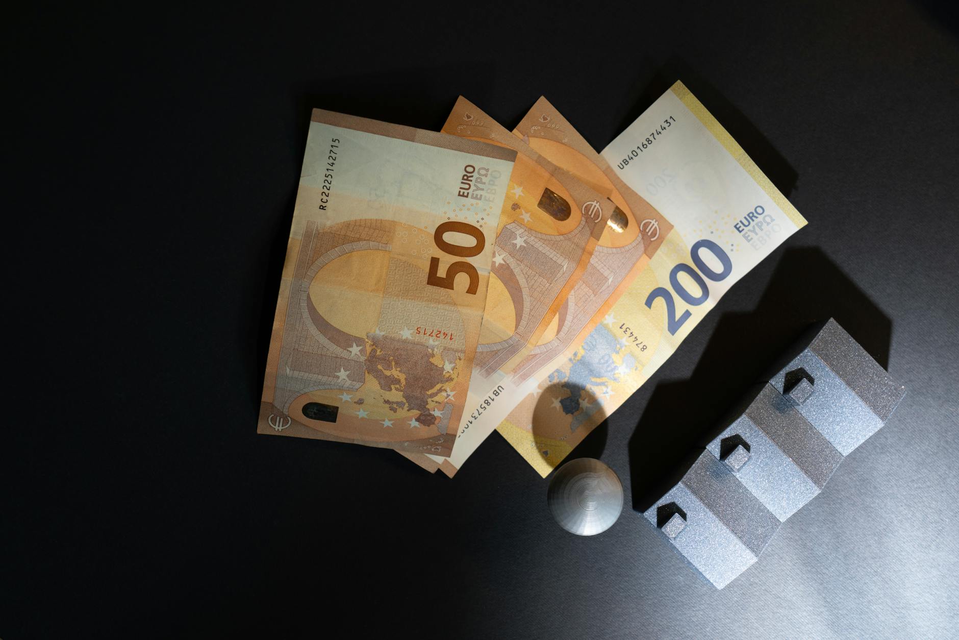 Banknoty euro i małe modele domów na ciemnym tle