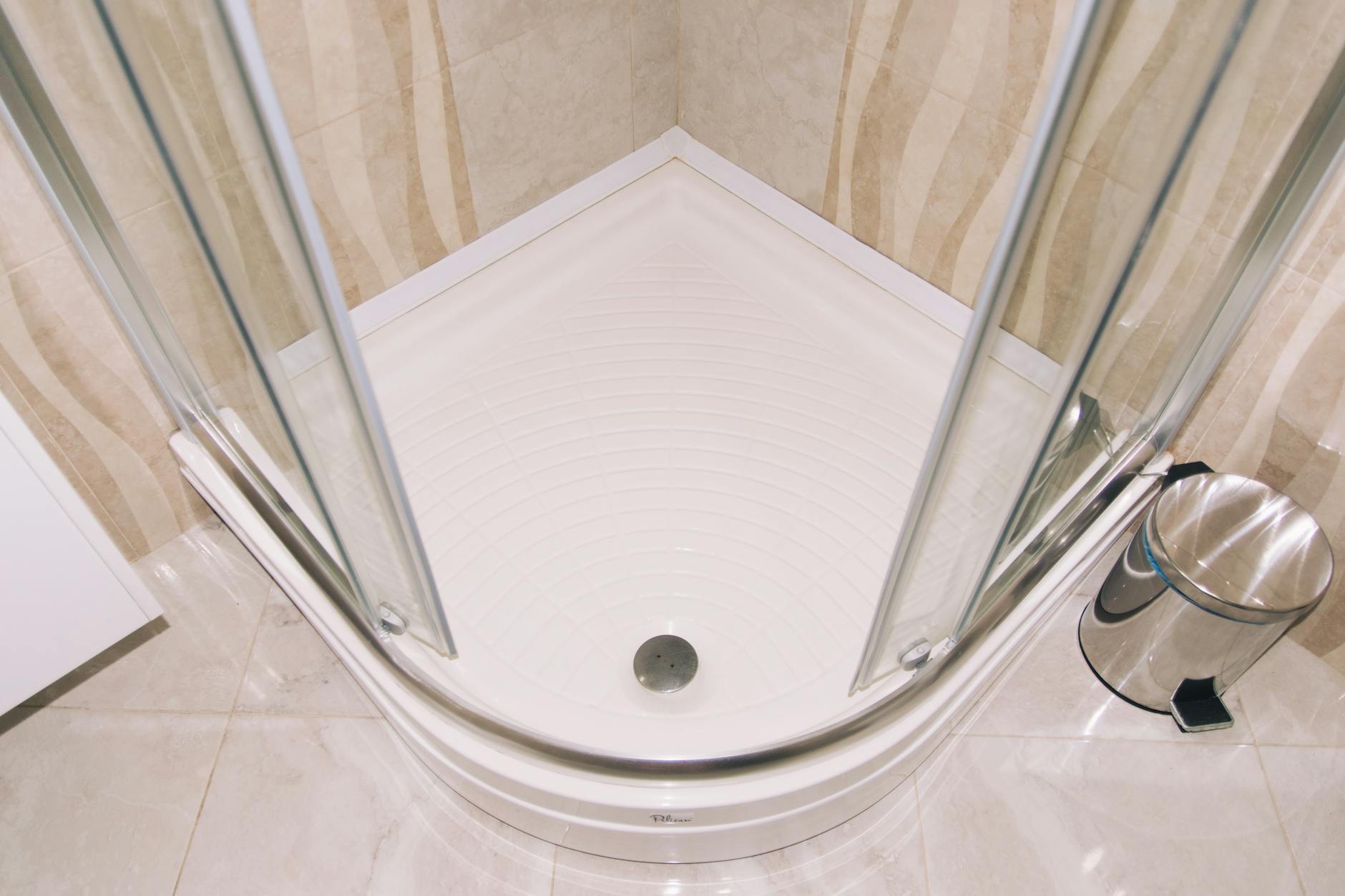 Nowoczesna kabina prysznicowa z przeszklonymi drzwiami w łazience z płytkami