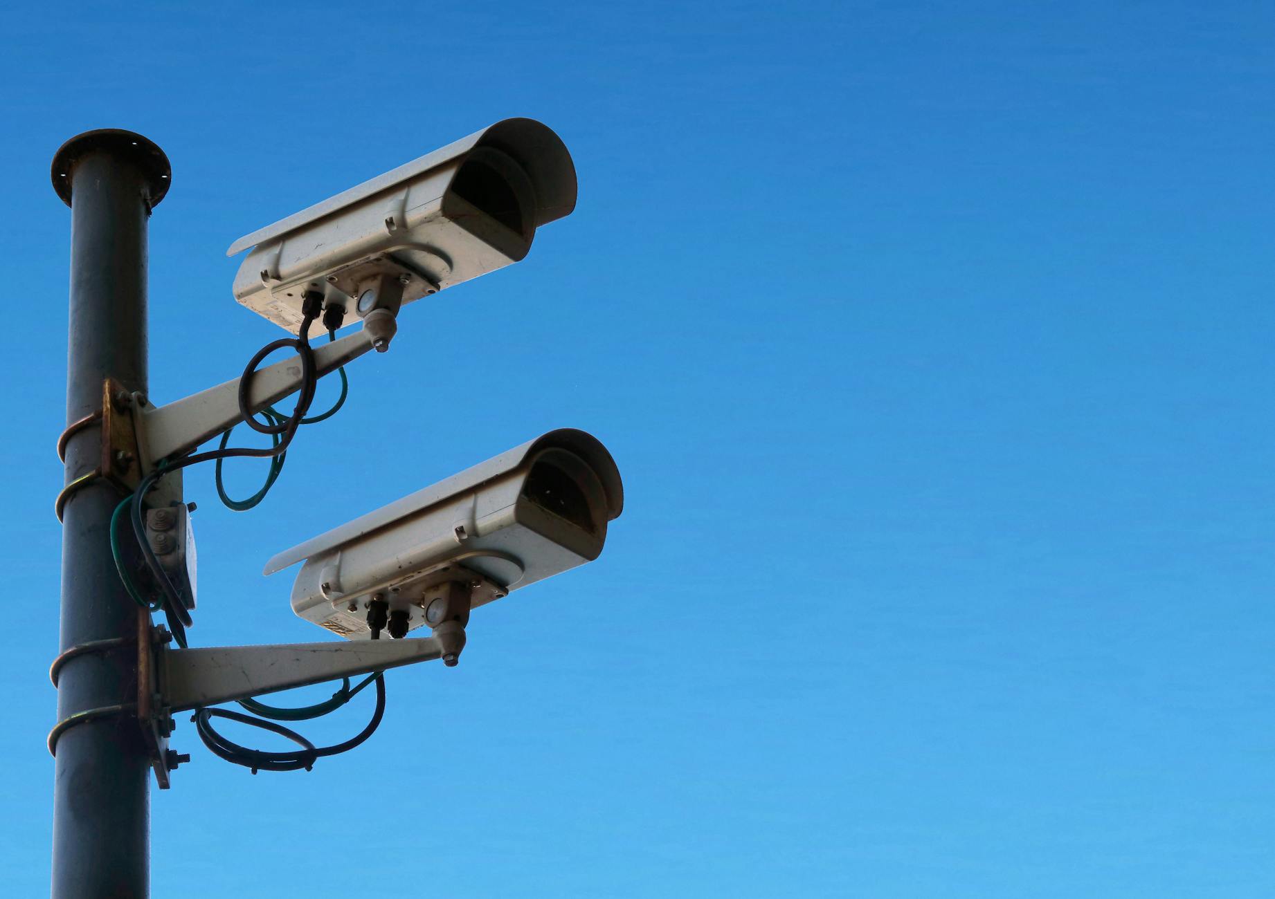 Zewnętrzna kamera monitoringu na czarnym słupie na tle nieba